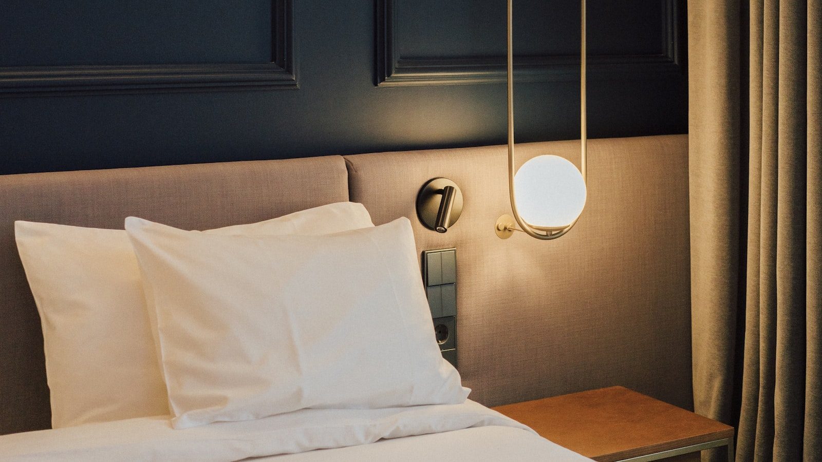 Hotelbett mit zwei weiß bezogenen Kissen und glatter Bettdecke.